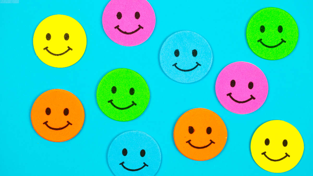 Viele bunte Smiley-Post-its auf blauem Grund