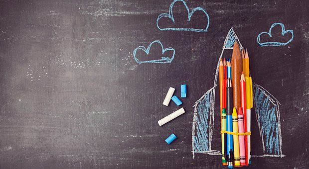 Eine mit Schulkreide auf eine Tafel gemalte Rakete startet