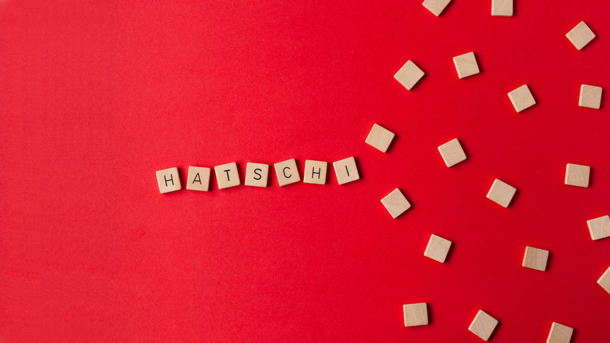 Scrabble-Steine mit dem Schriftzug Hatschi auf rotem Untergrund verdeutlichen das Phänomen Präsentismus