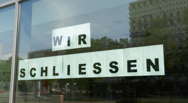 Leerer Laden, der "Wir schliessen" als Schild auf dem Schaufenster kleben hat.