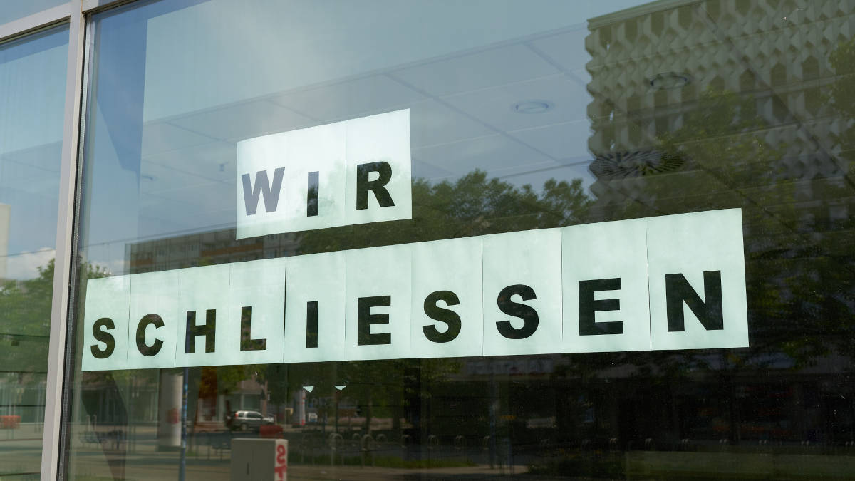 Leerer Laden, der "Wir schliessen" als Schild auf dem Schaufenster kleben hat.