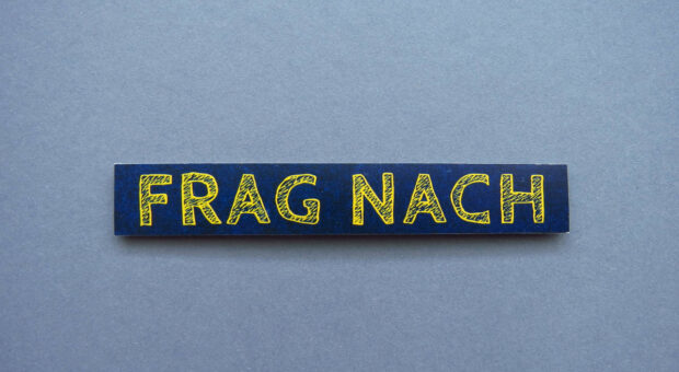 Schriftzug "FRAG NACH" auf blau-grauem Hintergrund