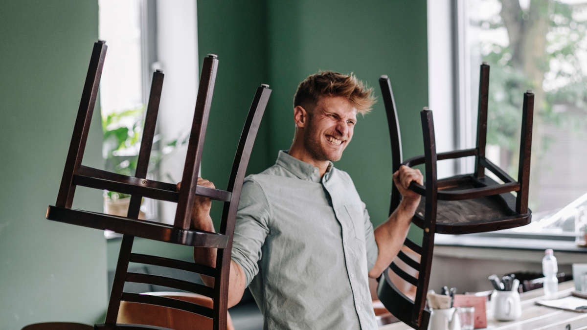 Bild eines Mannes, der zur Motiviation zwei Stühle in die Luft stemmt.