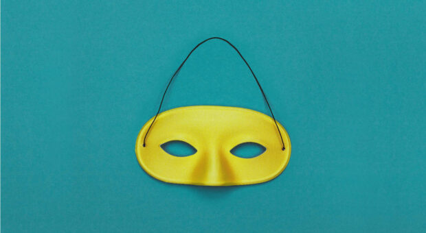 Gelbe Karnevalsmaske auf petrolfarbenem Hintergrund, als Symbolbild für das Thema Einkäufertricks kontern