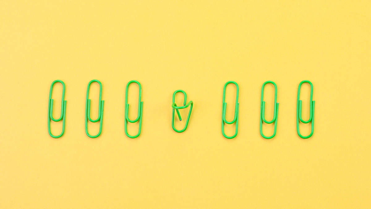 Eine Grafik mit 7 grünen Büroklammern auf gelbem Grund, von denen eine kaputt ist, als Illustration der SWOT-Analyse.