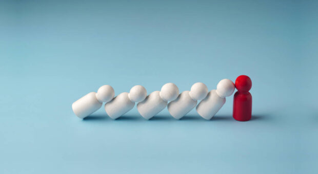 Weiße Brettspielfiguren kippen gegen eine rote und symbolisieren das Helfersyndrom von Chefs