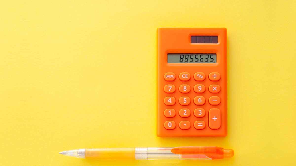 Bild eines orangenen Taschenrechners und eines Kugelschreibers auf gelbem Hintergrund.