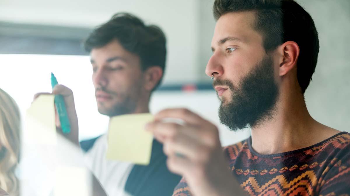 Zwei Männer kleben Post-it-Zettel