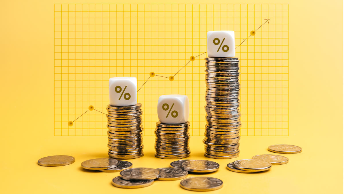 Vor gelbem Hintergrund stehen drei Stapel Münzen, auf jedem Stapel thront ein Würfel mit einem Prozentzeichen darauf.