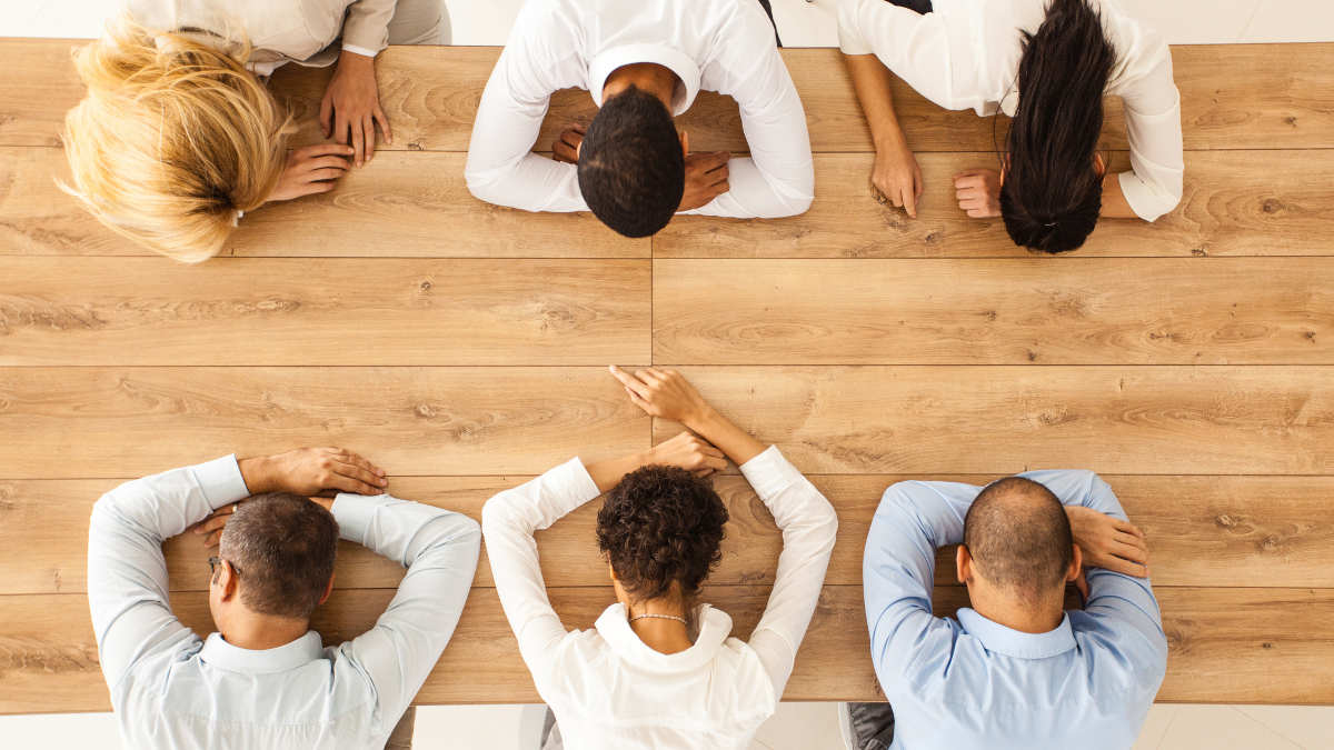 6 Personen sitzen an einem Tisch und halten ein Meeting ab, fünf Personen schlafen.