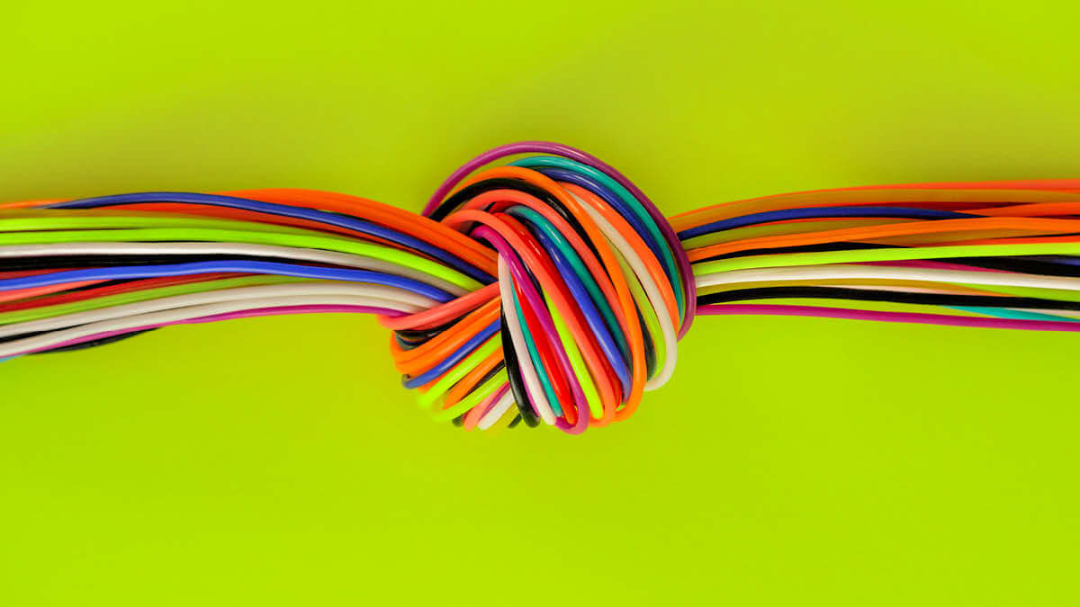 Knoten aus bunten Schnüren auf giftgrünem Hintergrund.