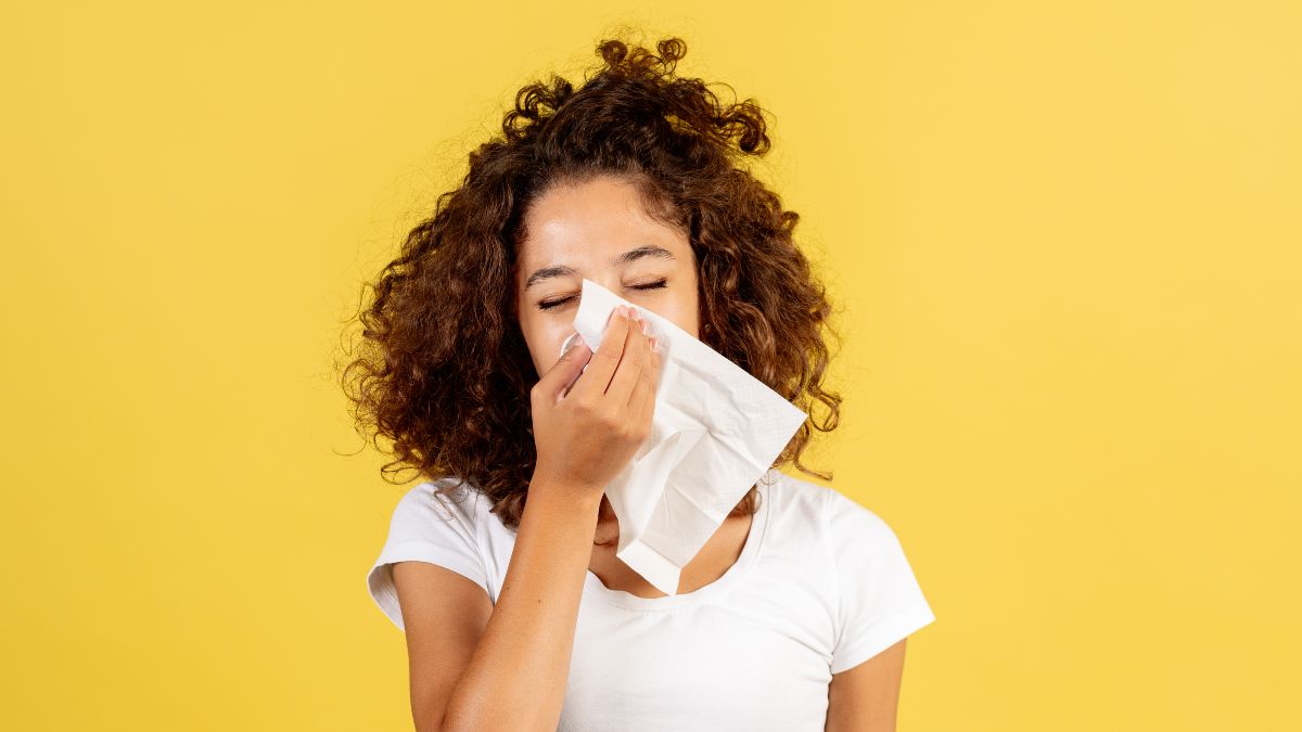 Eine Frau putzt ihre Nase mit einem Taschentuch