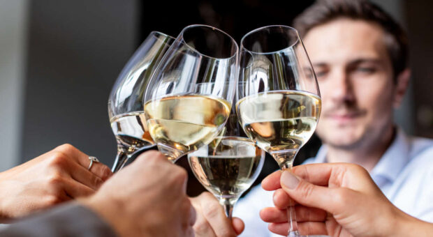 Mann stößt mit Arbeitskollegen an, Weingläser