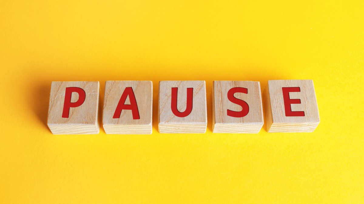Holzklötze mit dem Wort Pause auf gelbem Hintergrund