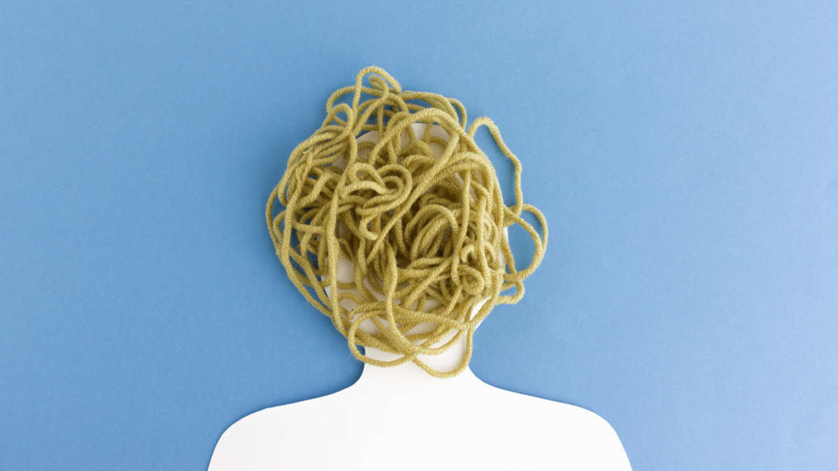 Grafik von einem Kopf vor weißem Hintergrund, in dem ein Wollfaden sich zu einem Chaos kringelt.