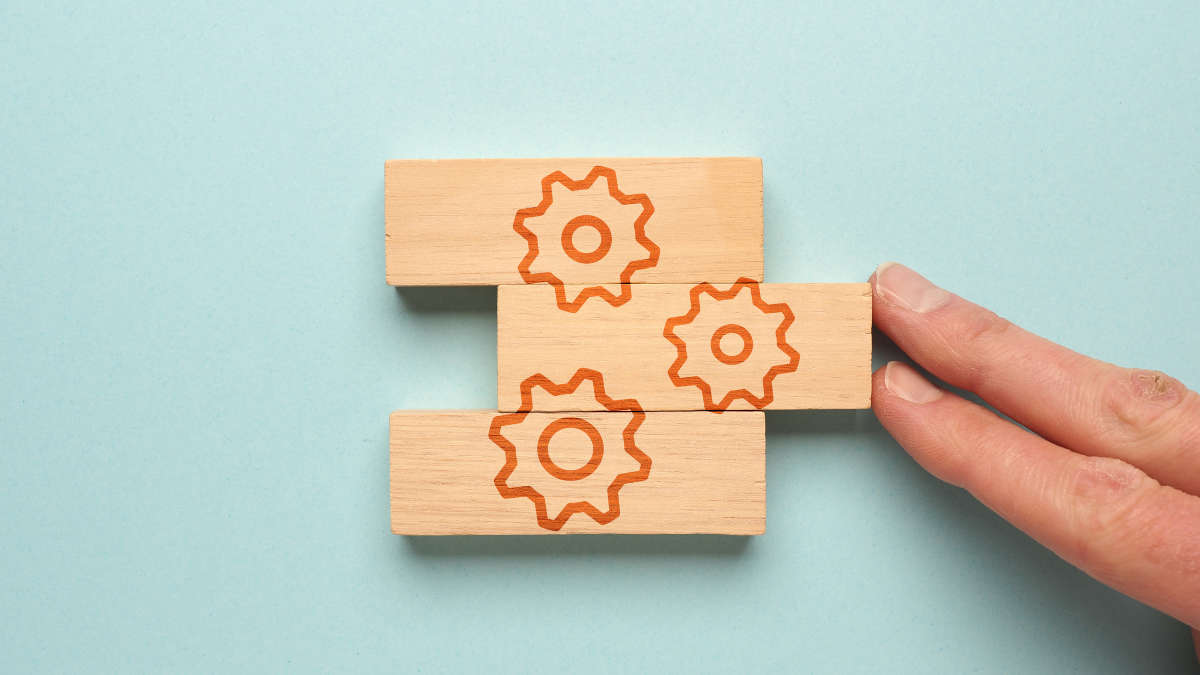 Drei Holzklötze, auf denen Zahnräder abgebildet sind.