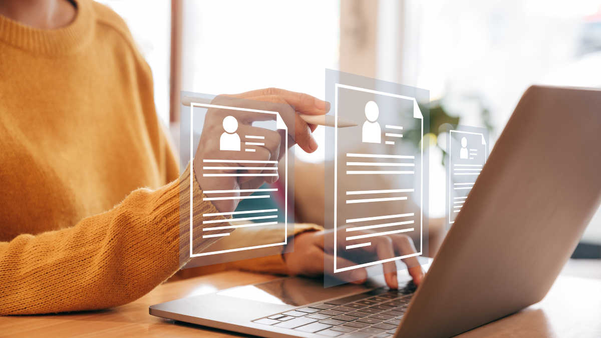Bild einer Person in orangenem Pullover an einem Laptop über dem digitale Lebensläufe schweben.