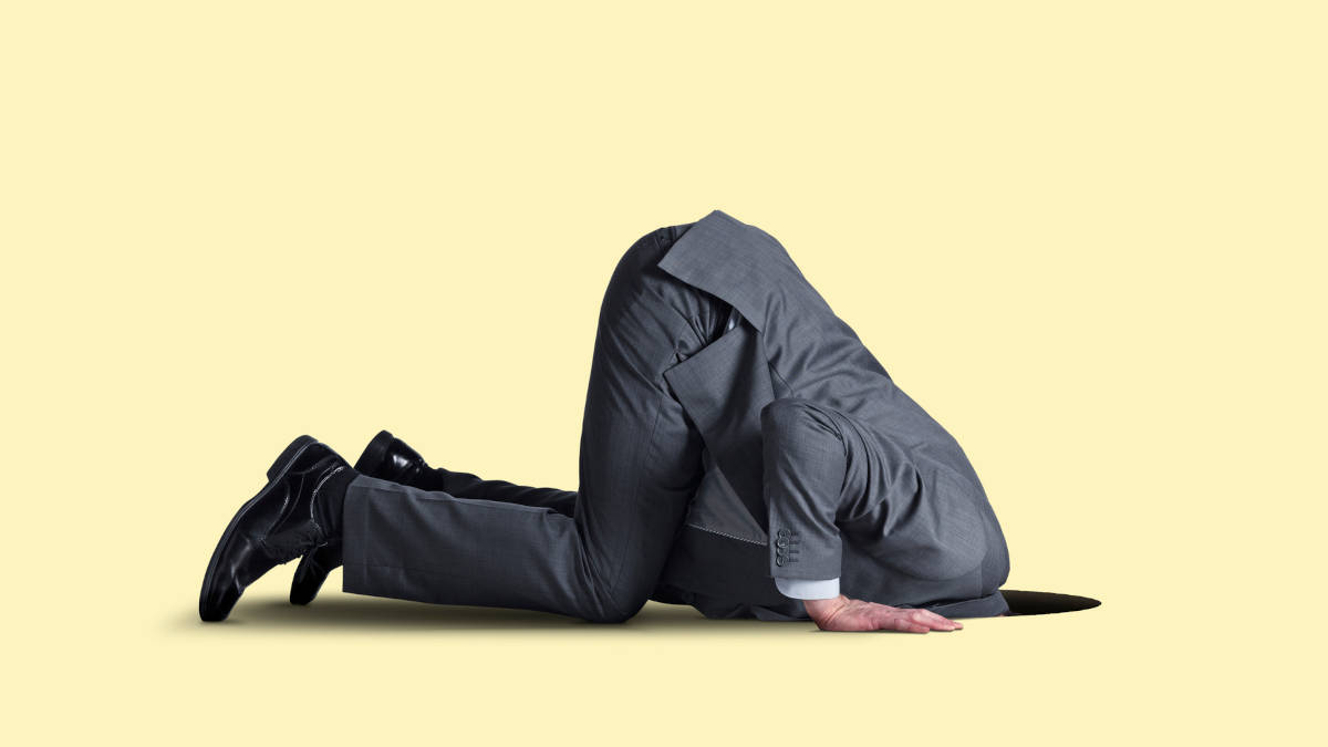 Mann im Anzug, Kopf in einem Loch im Boden