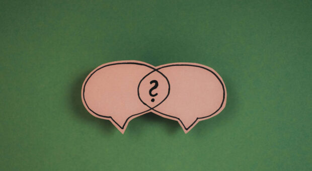 Zwei sich überschneidende Sprechblasen aus Pappe mit einem Fragezeichen in der Schnittmenge.
