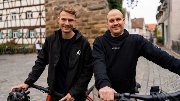 Zwei lächelnde Personen mit ihren Fahrrädern. 