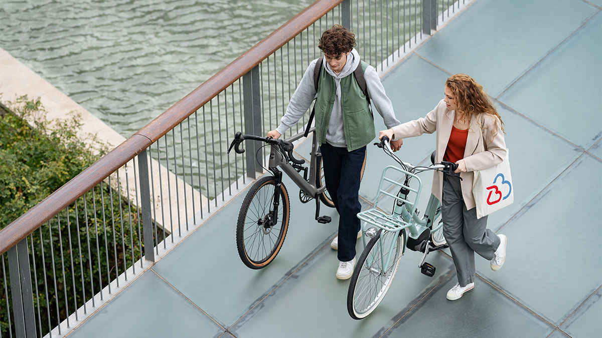 Zwei Personen schieben ihre Fahrräder über eine Brücke