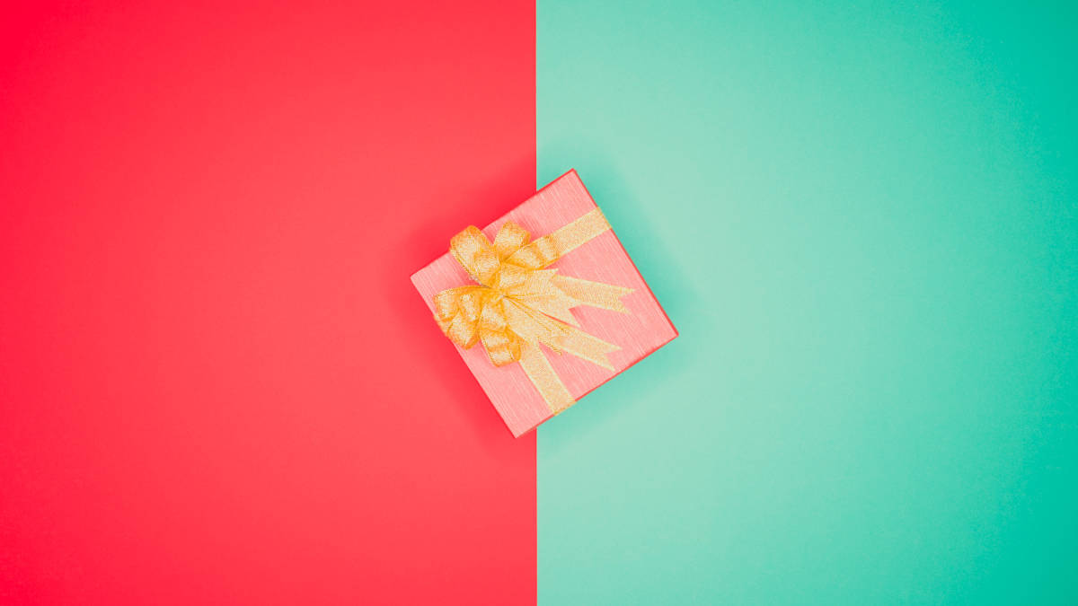 Geschenk von oben in der Mitte vor einem Hintergrund, der farblich exakt in rot und grün aufgeteilt ist.