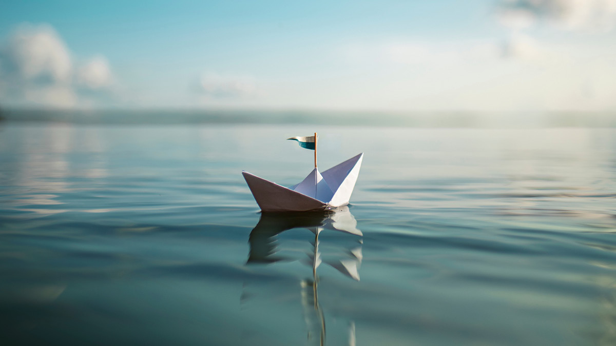 Ein einzelnes Papier-Schiffchen auf einem großen See