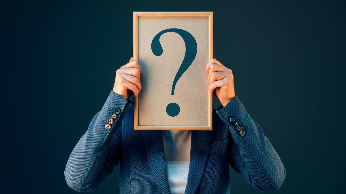 Businessfrau hält Bilderrahmen mit Fragezeichen vor ihr Gesicht