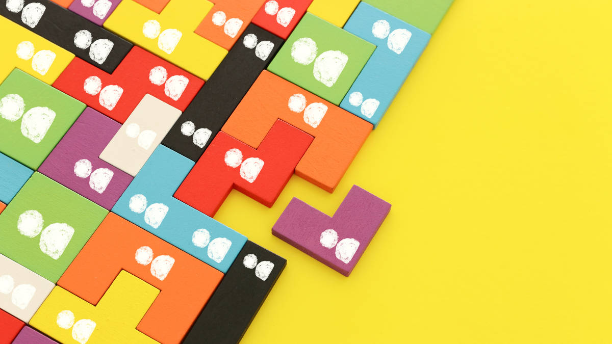 Perfekt ineinander liegende Tetris-Bausteine mit gezeichneten Männchen darauf auf gelbem Hintergrund.