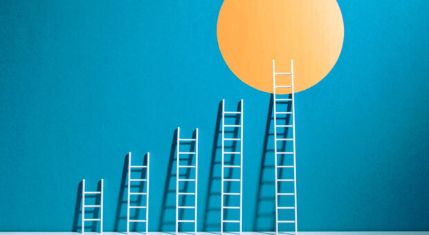 Das Bild hat einen blauen Hintergrund auf dem auch ein gelber Kreis zusehen ist. Davor sind 5 weiße Leitern, die Schritt für Schritt größer werden und die Letzte erreicht den gelben Kreis.