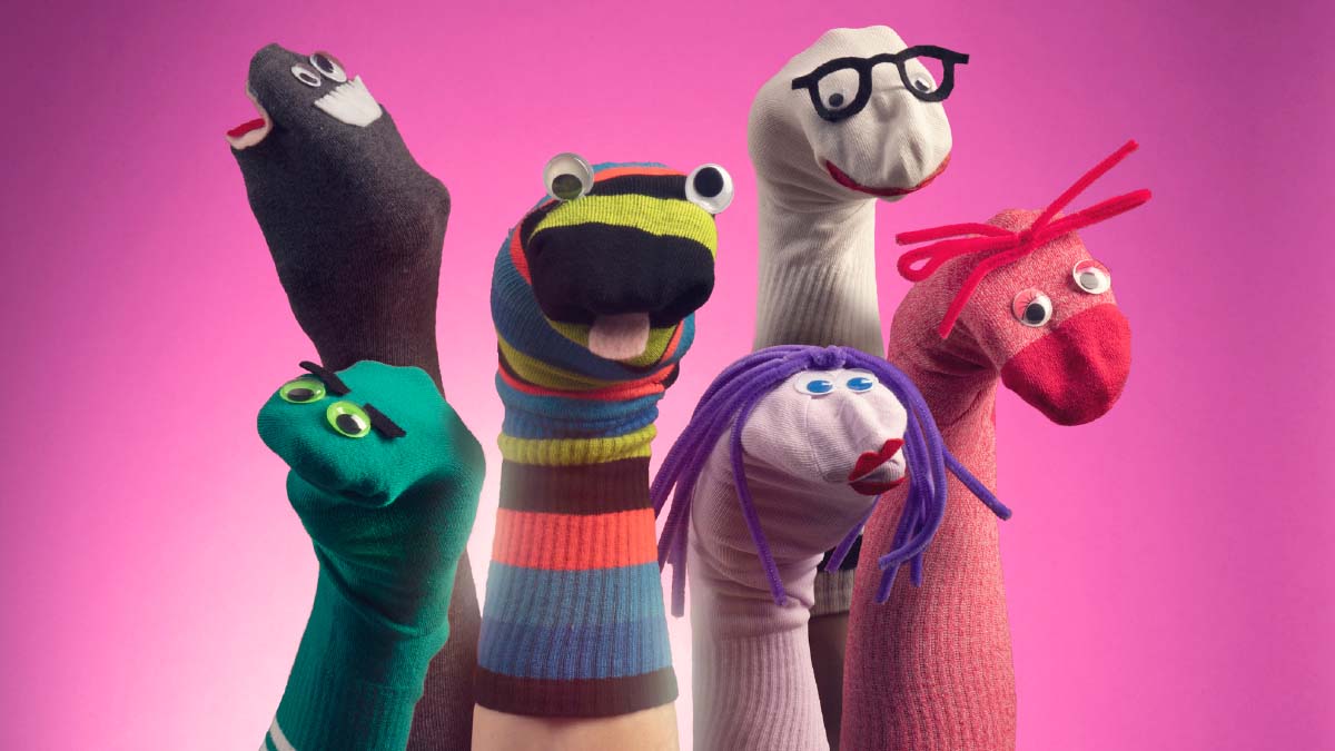 Verschiedene Socken-Handpuppen vor pinkem Hintergrund