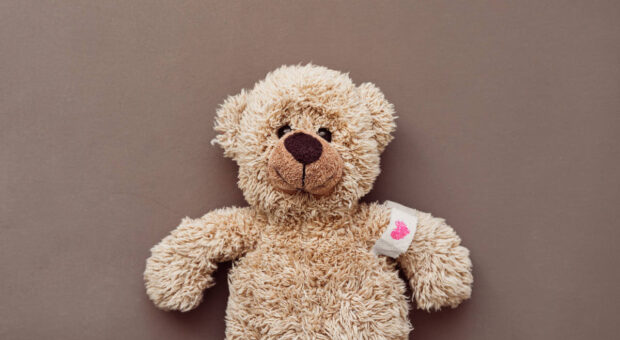 Ein Teddybär mit Pflaster am Arm, auf das ein Herz gemalt ist