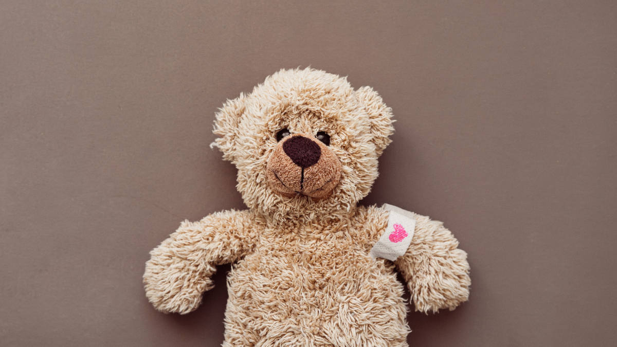 Ein Teddybär mit Pflaster am Arm, auf das ein Herz gemalt ist
