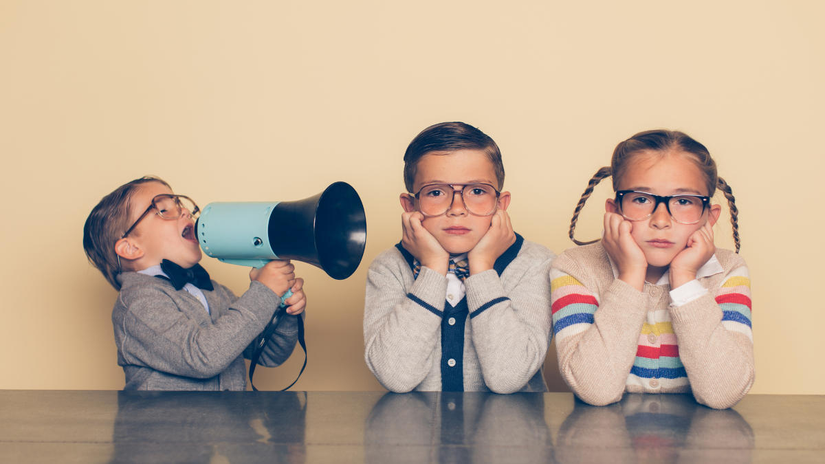 Kleiner Junge mit Megaphone und Fliege schreit einen Jungen und ein Mädchen an, die sich die Ohren zuhalten.