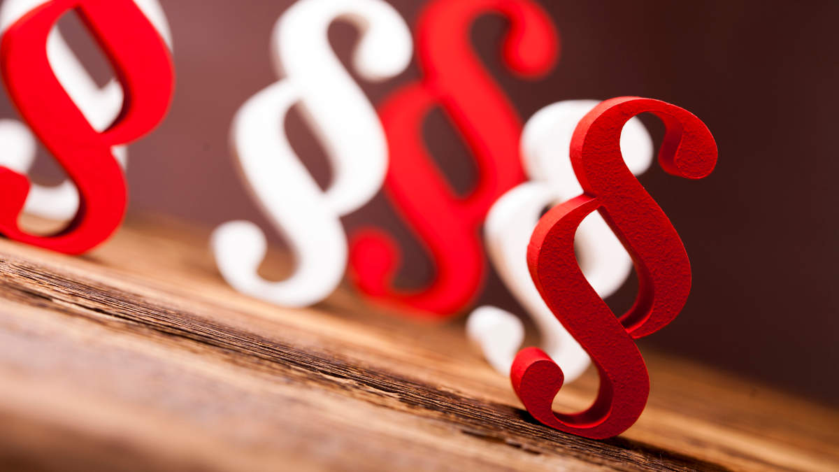 Paragraf-Zeichen in rot und weiß auf Holz