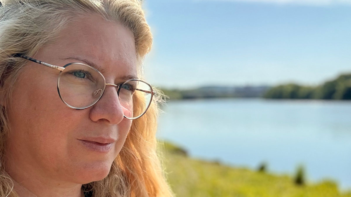 Die Unternehmerin Vanessa Weber blickt nachdenklich auf einen See.