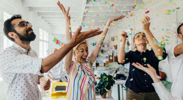 4 Personen, die mit Konfetti im Büro feiern