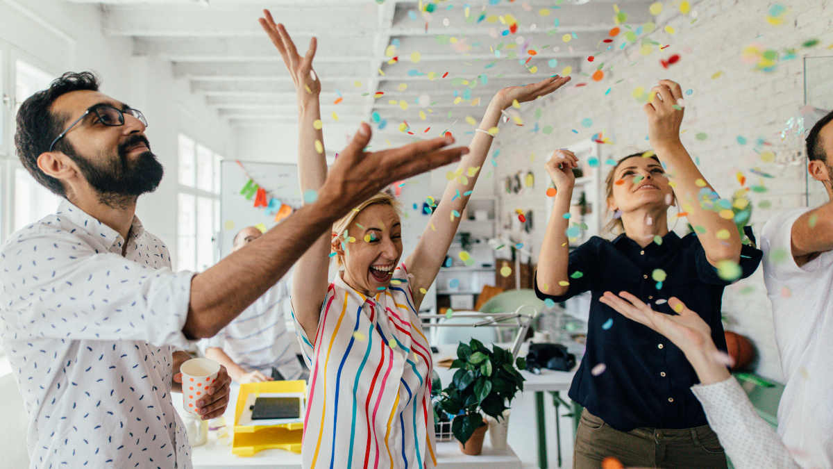 4 Personen, die mit Konfetti im Büro feiern