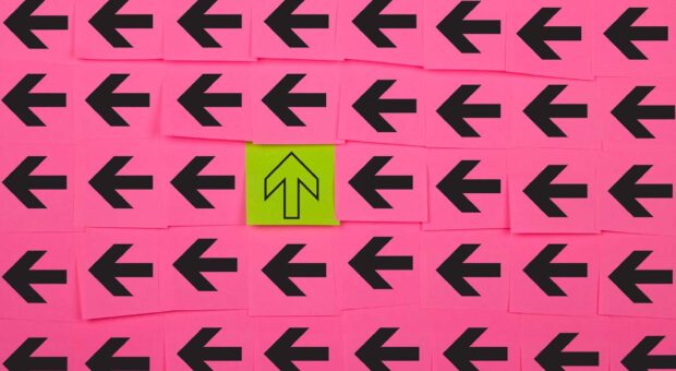 Viele schwarze Pfeile auf pinkem Hintergrund, die nach Links zeigen und in der Mitte ein gelber Pfeil, der nach oben zeigt