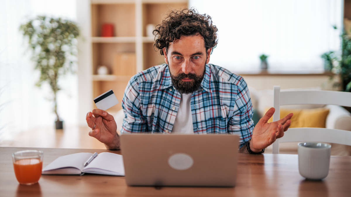Mann vor einem Laptop mit Kreditkarte