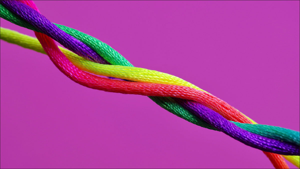 Ein Draht aus verschiedenen, bunten Strängen vor knalligem lila Hintergrund.
