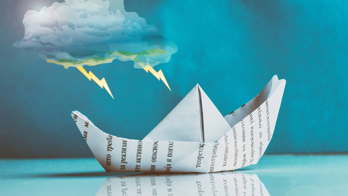 Ein Papierboot steht auf einer spiegelnden Oberfläche, darüber ist eine Gewitterwolke zu sehen.