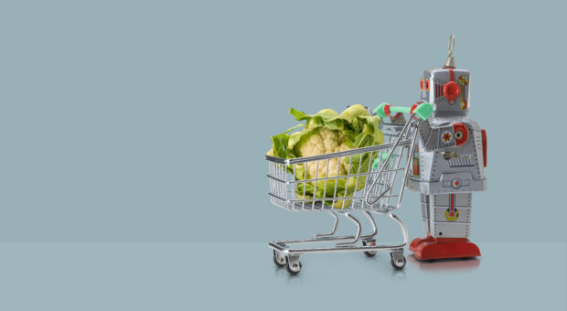 Ein kleiner Roboter schiebt einen Einkaufswagen mit einem überdimensionalen Blumenkohl