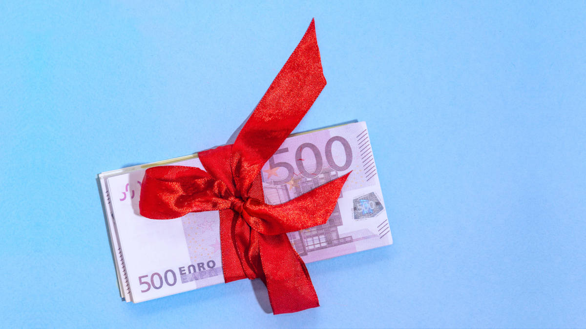 Fünfhundert-Euro-Scheine mit roter Schleife auf hellblauem Hintergrund.