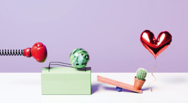 Absurdes Modell einer Kettenreaktion aus Boxhandschuh, Bowlingkugel und Luftballon